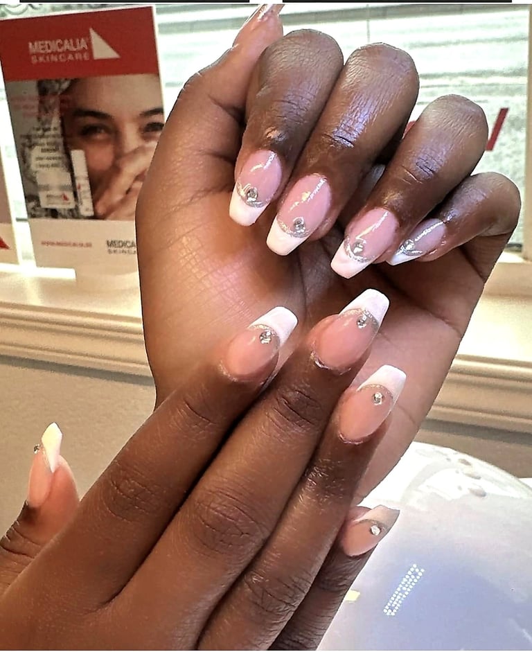 Close-up of a hand displaying elegant pink and white ombre nail art with rhinestone accents and nude gradient tips